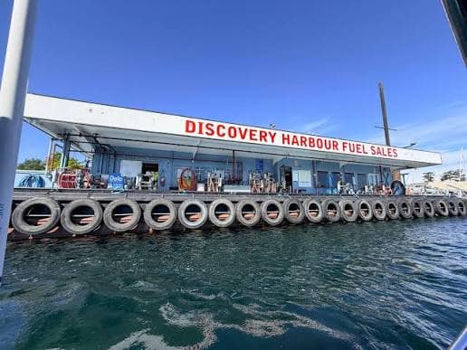 Discovery Harbour Fuel Sales dock seen from the water, with its red sign and tire-fendered float